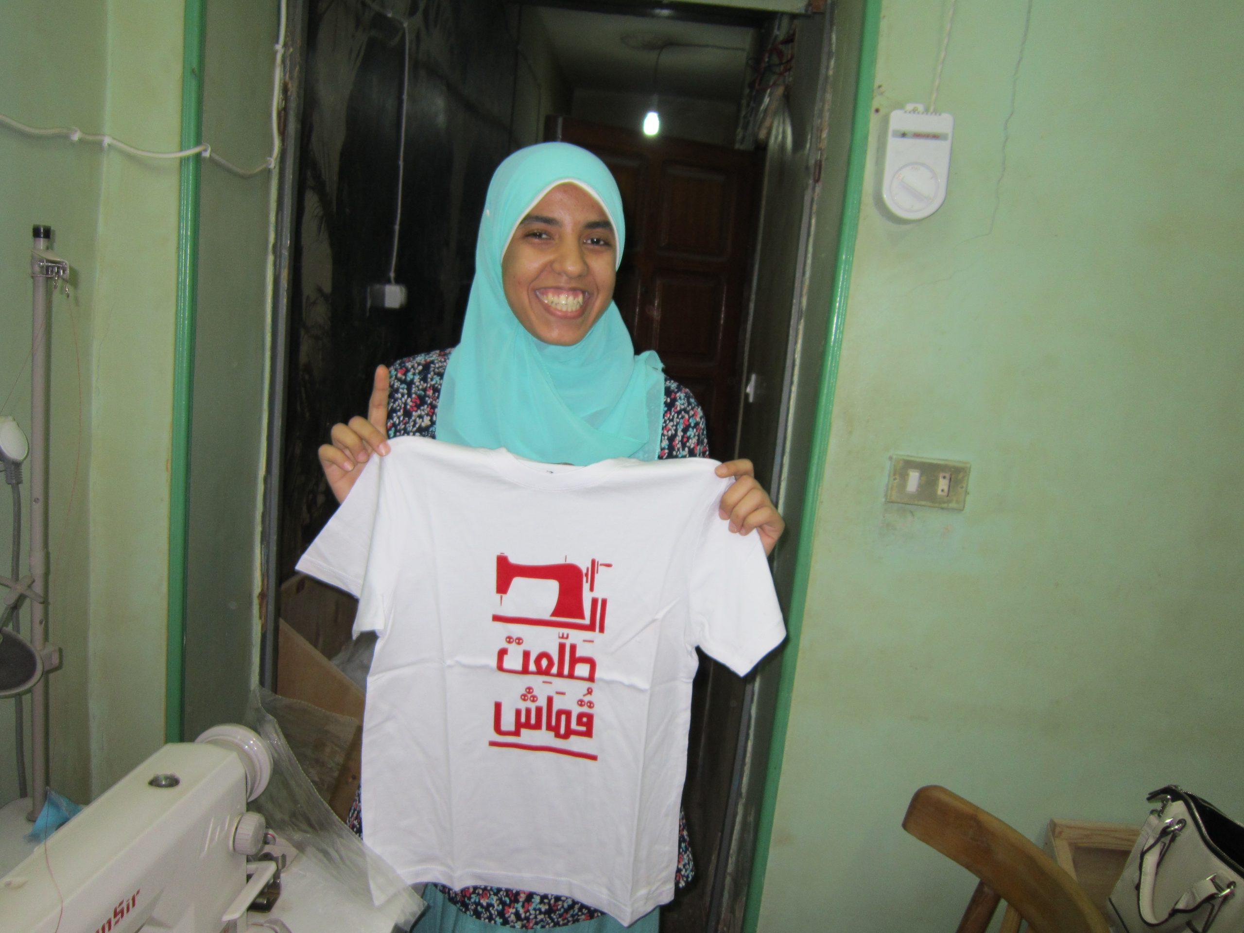 Yasmine Heika montre le premier T-shirt confectionné par les femmes du quartier informel
