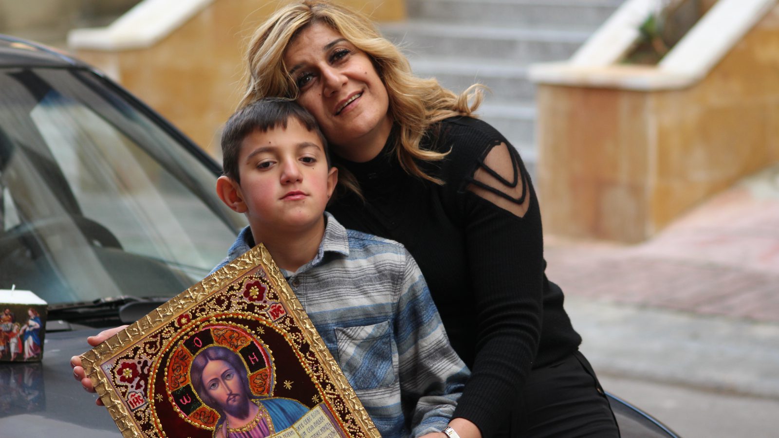 Faten Merhi and her son Loubnan pose on the hood of their car with 3 works created by Faten during the workshop given by the NGO La Voix de la Femme and funded by the EU as part of the DAWRIC project. Chiyah, Lebanon