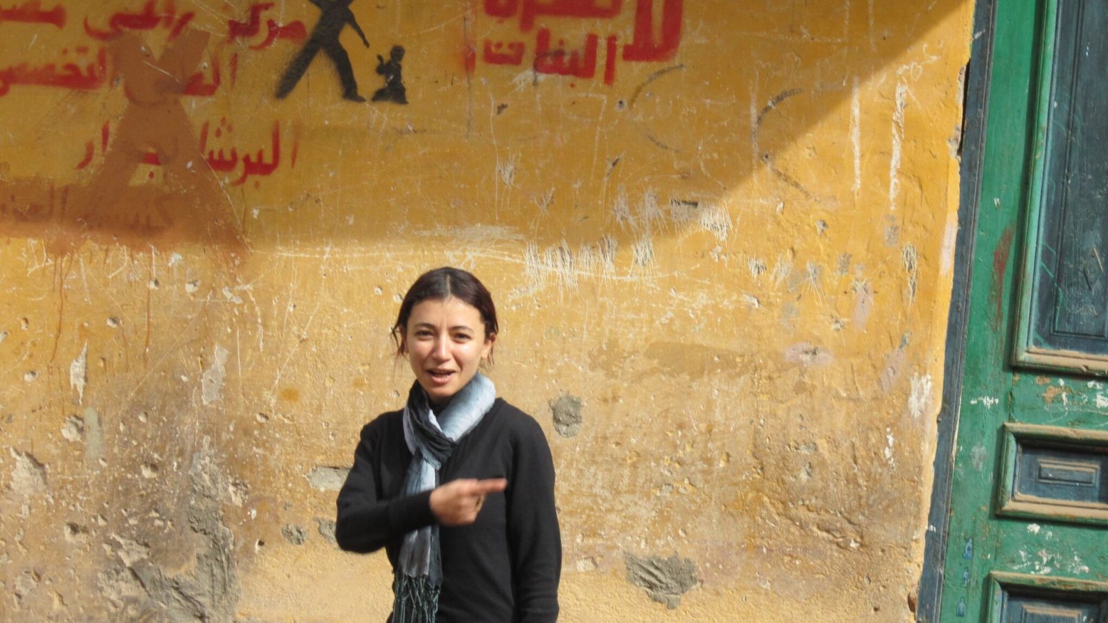 Youstina, avec en arrière plan un graffiti de l'association: Non à la violence contre les filles!